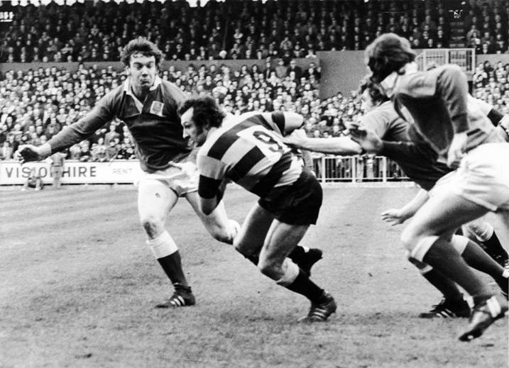 Gareth Edwards looks to evade the clutches of the Llanelli cover during a clash at a packed Arms Park on February 23, 1974